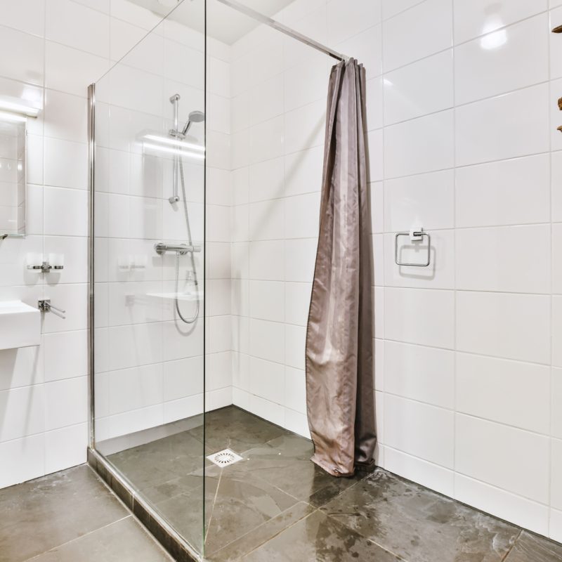 Contemporary luxury washroom with glass shower cabin and white basin under mirror with illumination