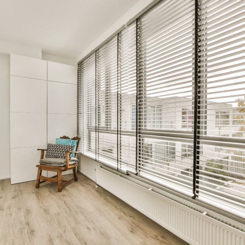 a room with wood flooring and white shutters on the windows looking out onto an outside cityscapea