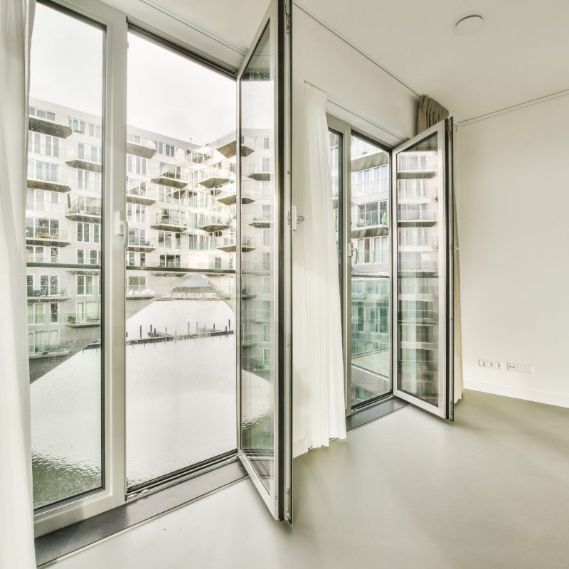 the inside of a room with white walls and glass doors that look out onto a canal in the distance from the outside