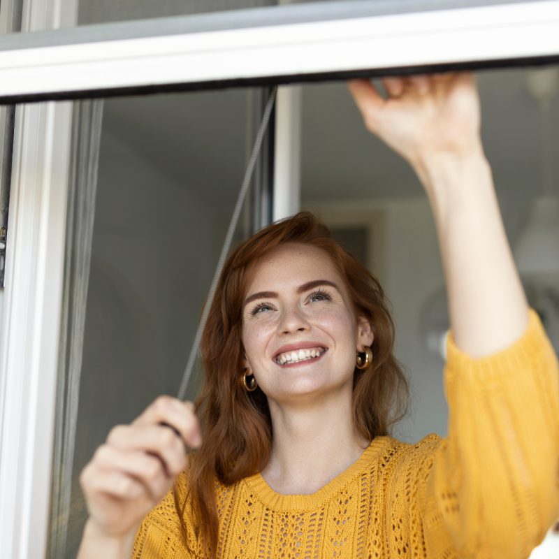 Woman hand hold retractable pleated insect screen holder to open or close the window ,mosquito nets